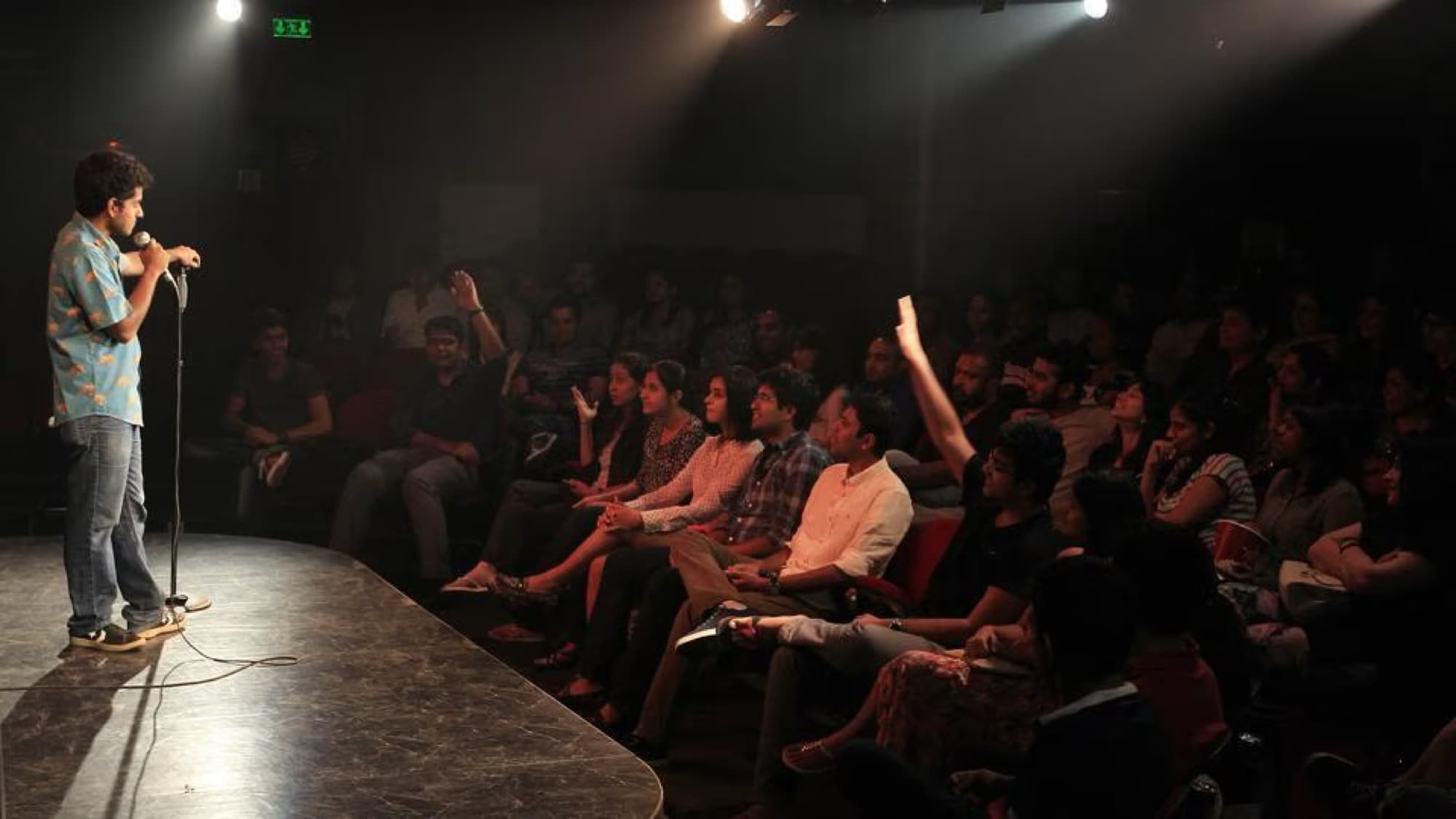 A comic working a full room from a low stage.