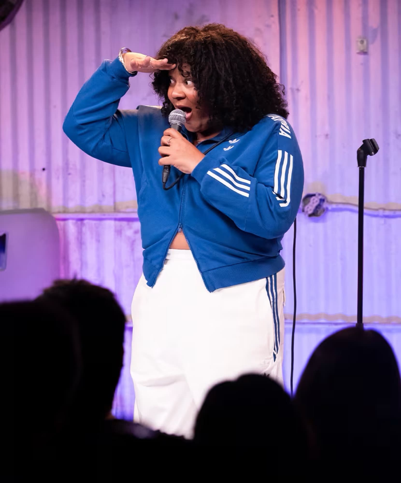 A comic mid-punchline under a stage wash.