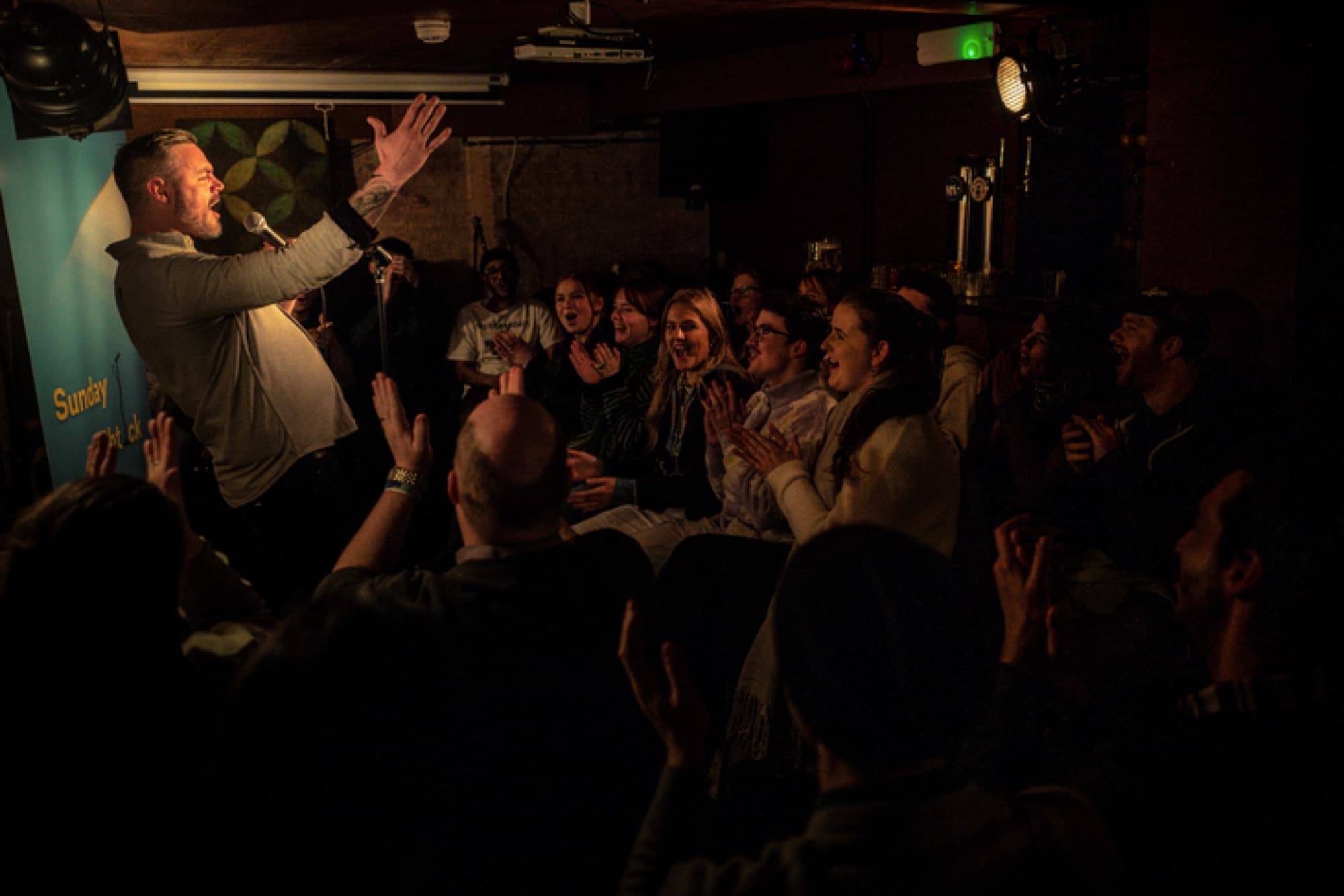 A comic working a laughing crowd from the stage.